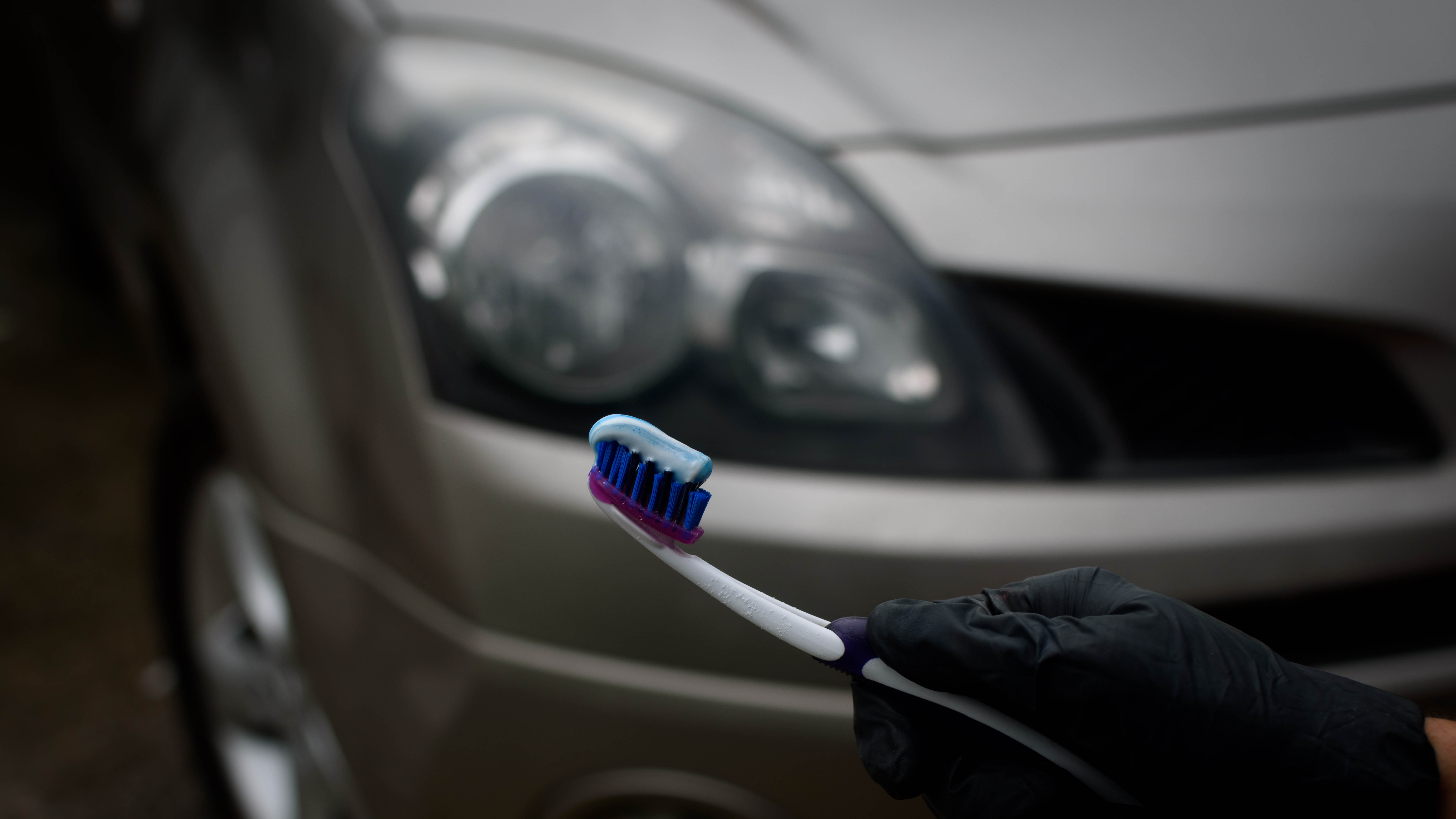 Bir arabanın farlarının önünde diş macunu tutan bir diş fırçası