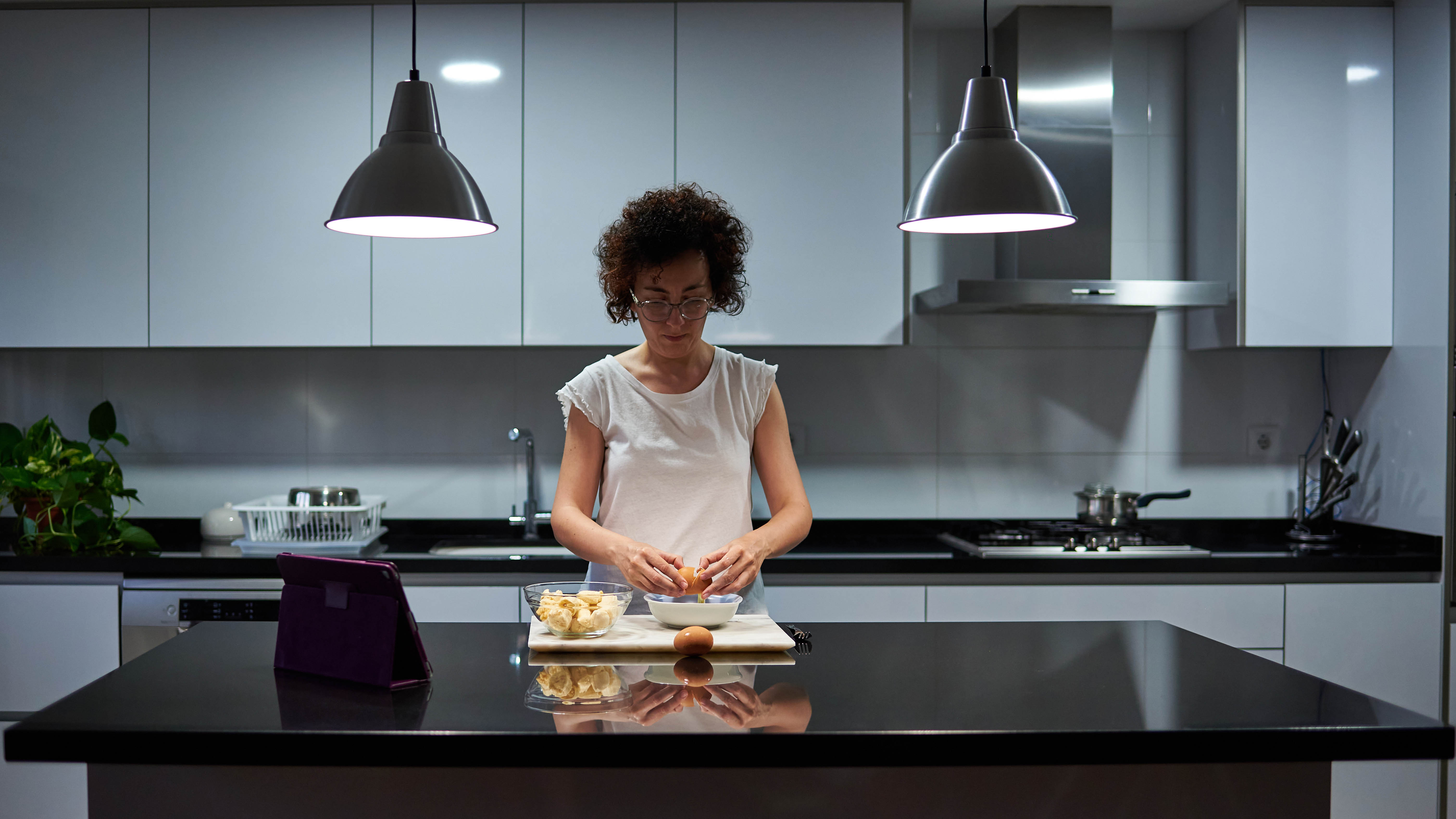 Işık açıkken geceleri mutfağında yemek hazırlayan bir kadın