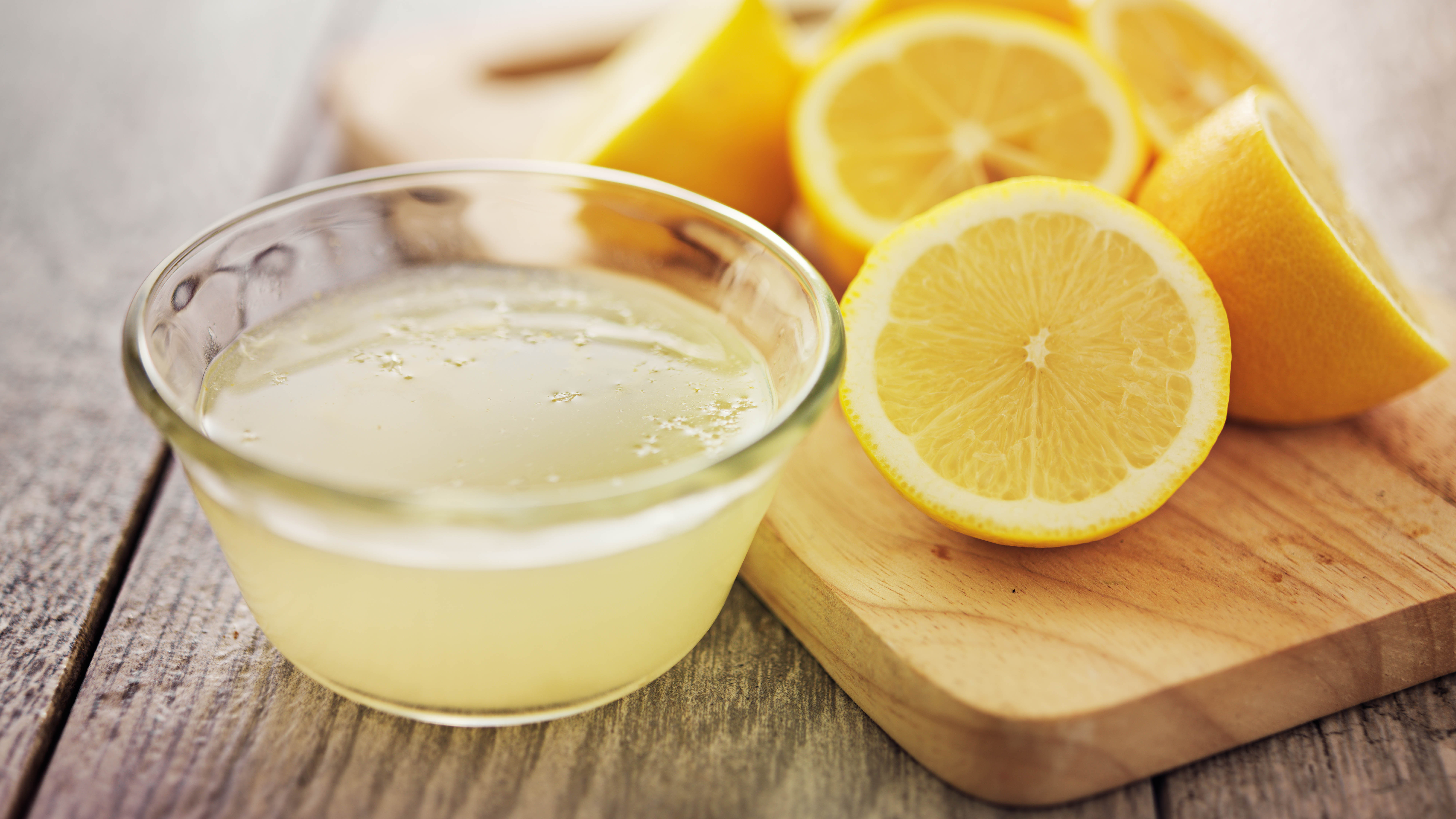 Limonların yanında bir kase limon suyu