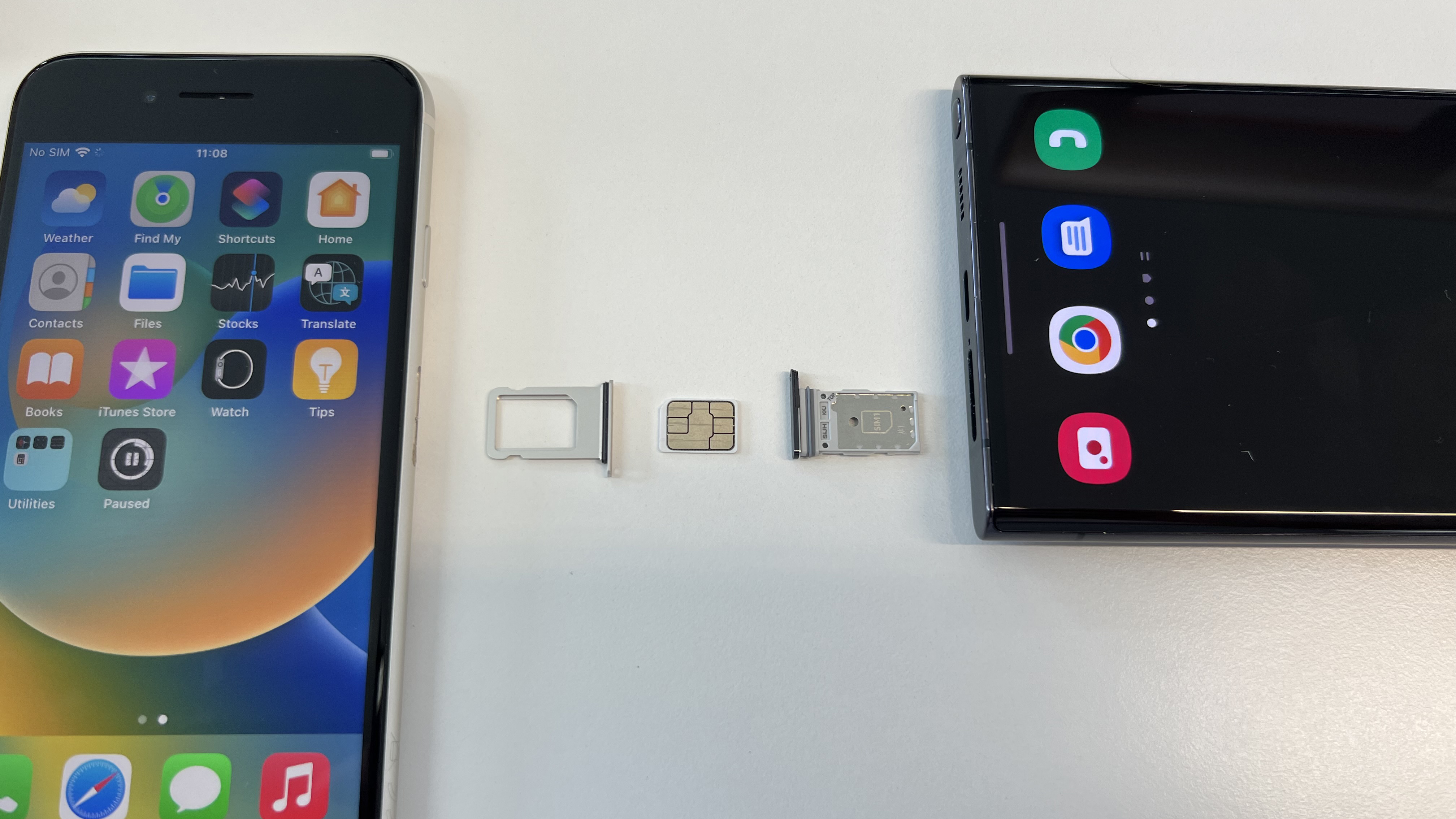 SIM tepsileri çıkarılmış ve aralarına nano SIM kart yerleştirilmiş bir iPhone SE 2022 ve Samsung Galaxy S22 Ultra