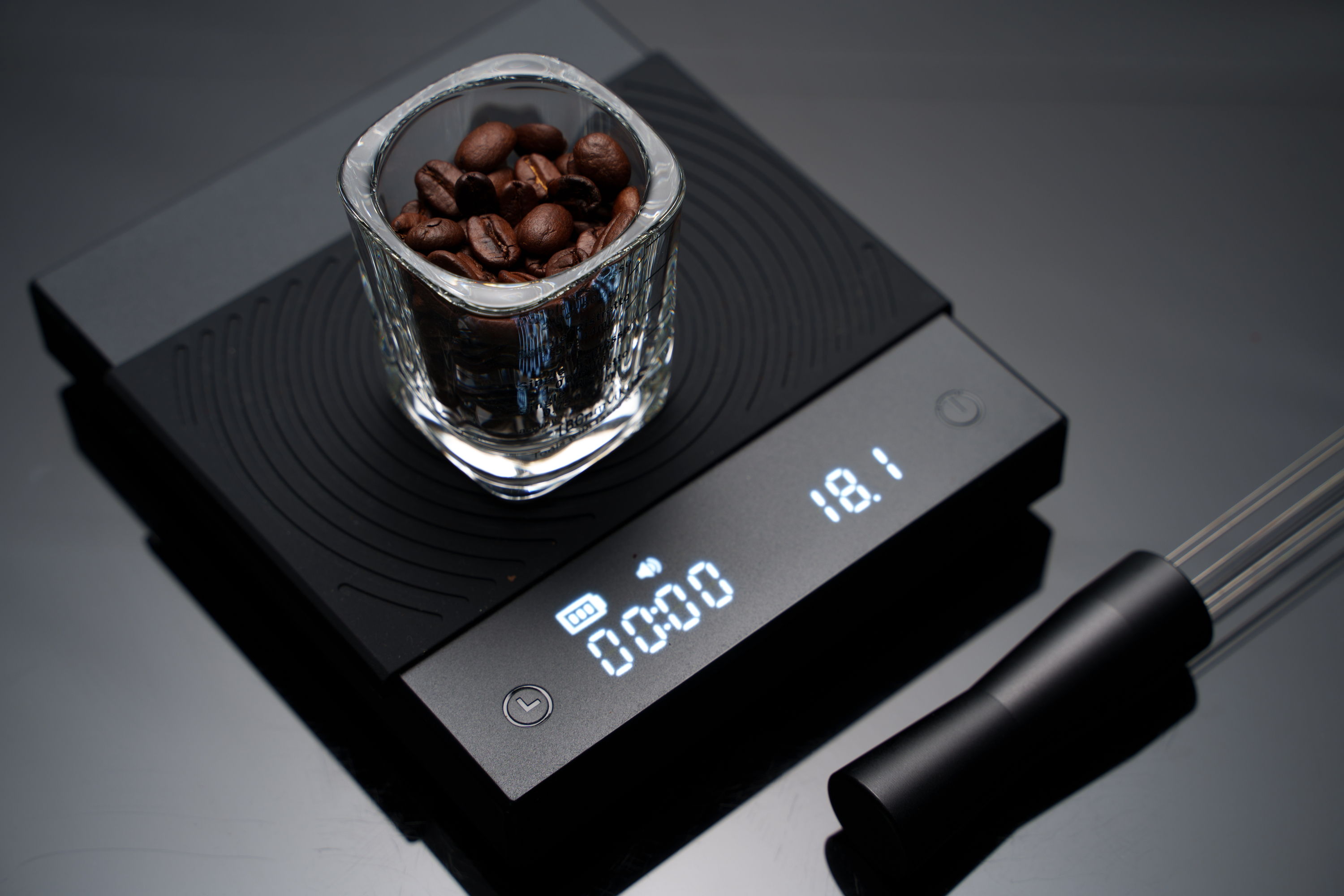Siyah kahve pullarının üzerine yerleştirilmiş kahve çekirdekleriyle dolu bir espresso bardağı ve koyu renkli bir tezgah