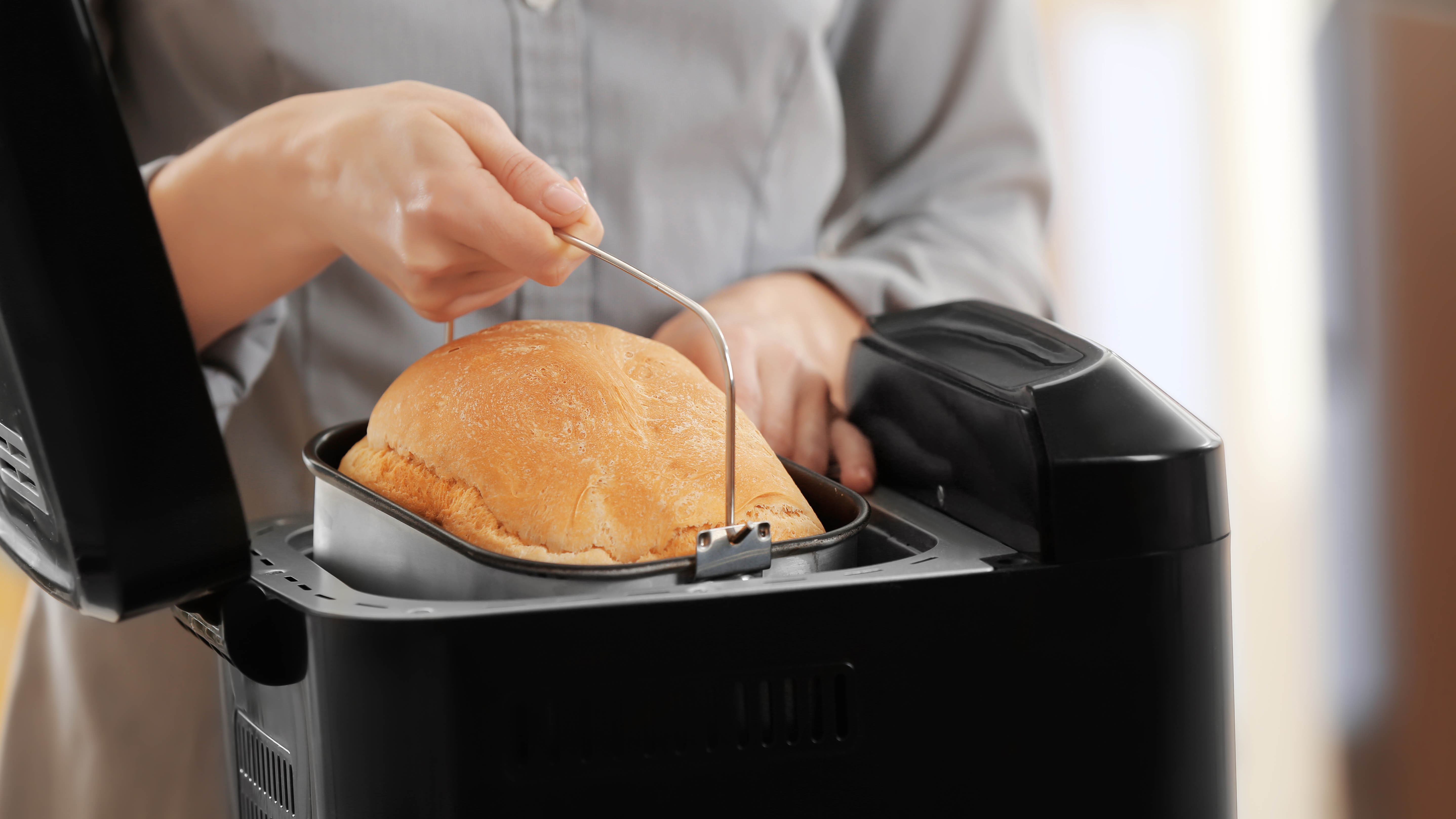 Ekmek makinesinden bir somun ekmek çıkarılıyor