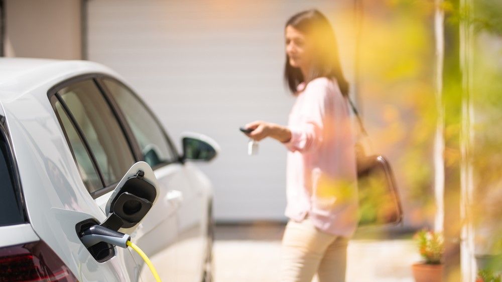 A woman locking a charging electric car